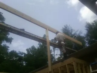 Carpenter setting a ridge beam over a new addition frame — Ice Dam Removal by Roofing Brothers in Vida