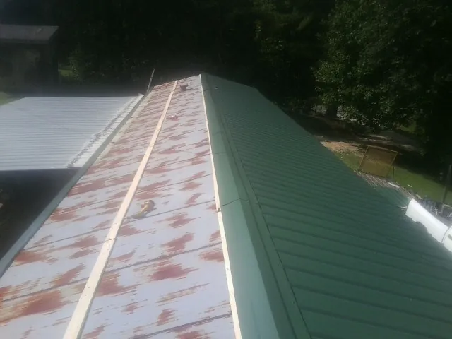 Old rusted panels beside newly installed green metal roofing — Wind Damage Roof Repair by Roofing Brothers in Vida