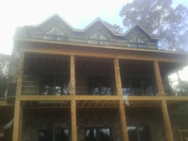 Dormers and porch framing on a large log home under construction — Roof Coating work by our crew in Vida