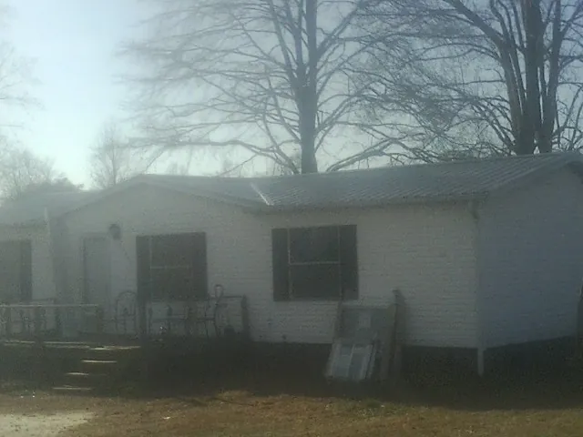 New metal roof on a white painted brick home on a foggy morning in Vida
