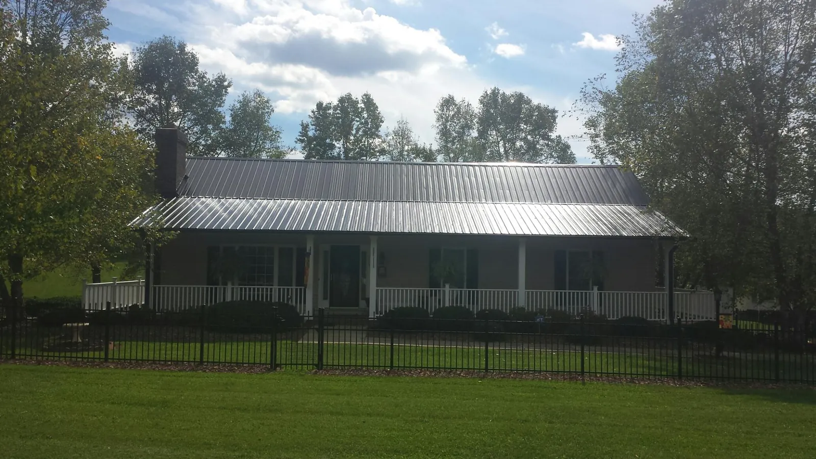 Gray metal roof on a brick ranch with a full width front porch — Gutter Guard Installation work by our crew in Vida