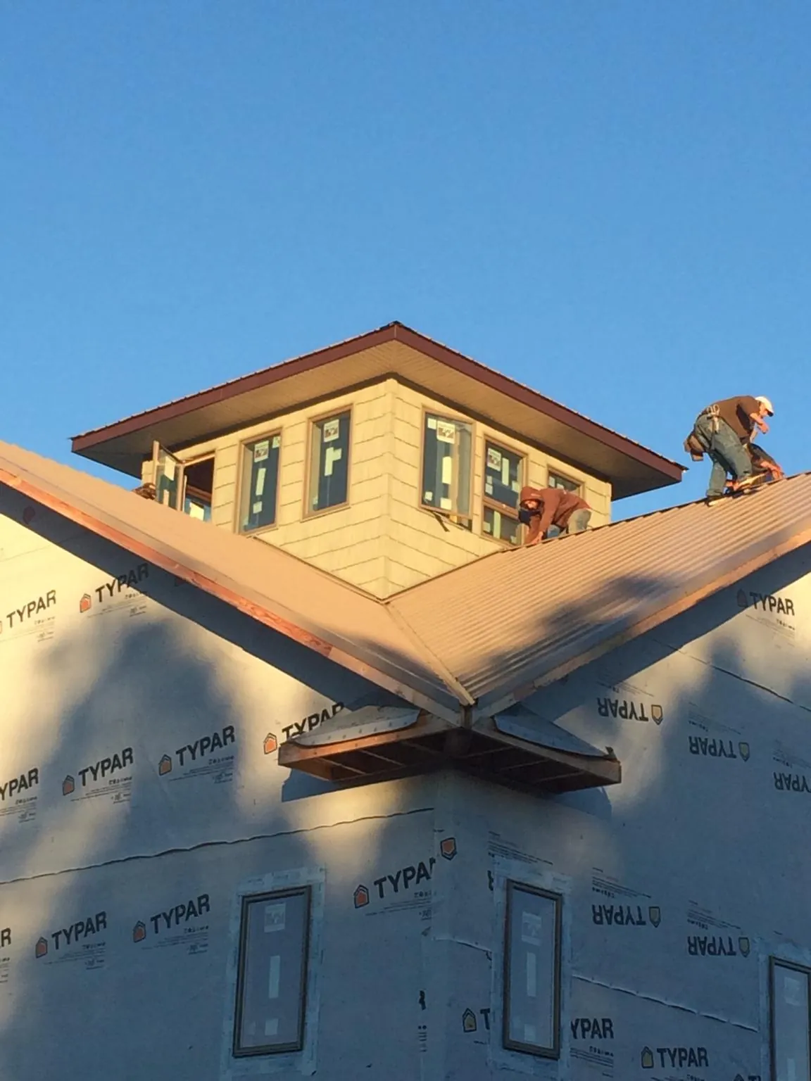 Roofers working around a rooftop cupola on a new metal roof at sunset — Roof Waterproofing in Vida by Roofing Brothers